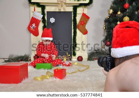 Santa mom making photo of her little son in a New Year pajama