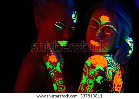 two girls in neon light pictures neon colors on the body, fire and ice