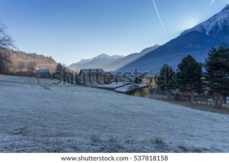winter landscape, meadow and trees with frost, snow-covered mountains background