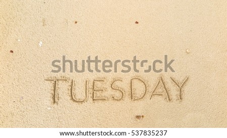 Handwriting words "TUESDAY" on sand of beach