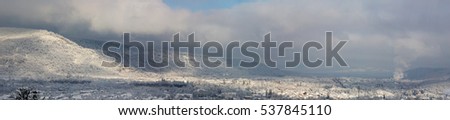 winter landscape. village in the valley forest hills covered with snow and clouds, shallow depth of field