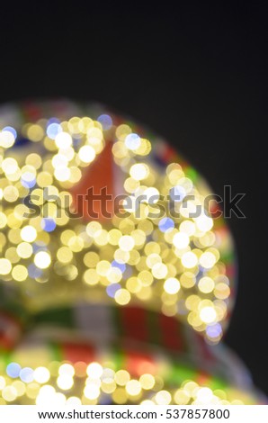 Blurred silhouette of the face shapes from bright light bulb snowman with a carrot nose hat and scarf. Bokeh. The festive decoration of the city on the night of Christmas. Blurred focus. 