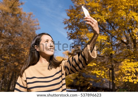 Woman taking self image by mobile phone in Autumn