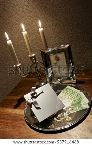 Five hundred Euros, pearls and surprise gift on silver tray arranged with candle holder on wooden table; Christmas or birthday gifts; Luxurious gifts
