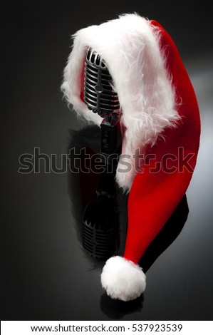Carols and Christmas music concept with a microphone wearing a santa hat with copy space