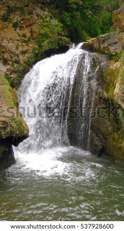 a low waterfall pours between huge rocks from a rock