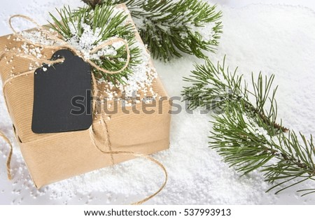 Present for any holidays concept. Brown gift box with copy space for text with snow on white background. Package with tag for Christmas, New Year, Valentine day or Birthday.