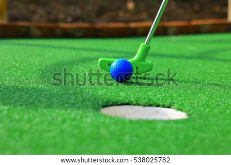 A club prepares to hit a ball during a mini golf game Royalty-Free Stock Photo #538025782