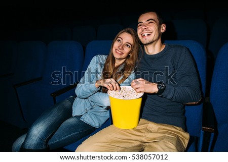 Cinema day. Young happy couple watching funny movie in cinema at their romantic date. World cinema day.