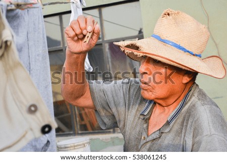 Old latin man hanging clothes 
