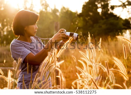 Soft Focus of Southeast Asian Woman Taking Photo Outdoor at Field in Sunset Time