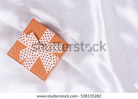 Flat lay brown gift box with bow over white satin