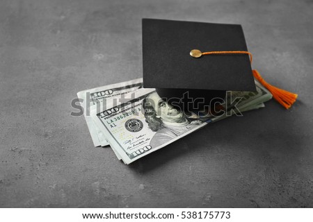 Graduation hat and dollar banknotes on table. Tuition fees concept Royalty-Free Stock Photo #538175773