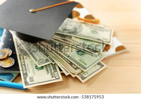 School supplies, graduation hat, dollar banknotes and coins on wooden table. Pocket money concept Royalty-Free Stock Photo #538175953