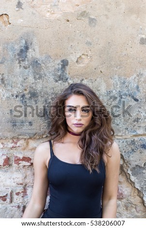 Gorgeous girl with a choker standing against brick wall