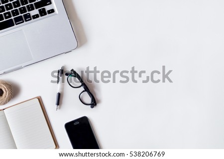 White office desk table with laptop, pen, smartphone, rope, and notebook. Top view with copy space, flat lay.