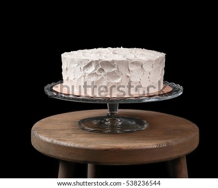 Delicious cake on stand against black background