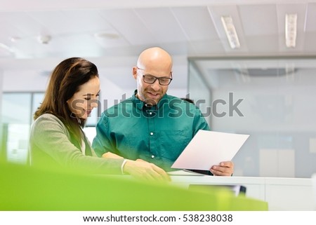 Businessman and businesswoman with paperwork in office