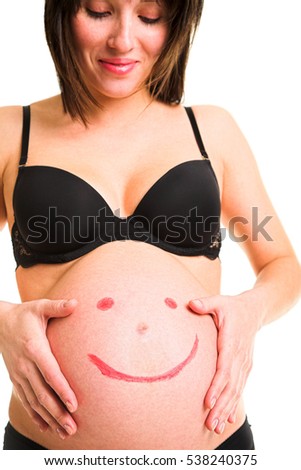 Happy pregnant woman with smiling funny face painted on her belly 