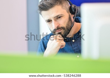Thoughtful mid adult businessman wearing headset at office