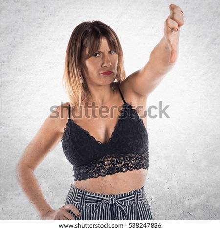 Pretty woman making bad signal on textured background