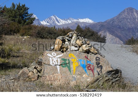 Prayer stones as a form of prayer in Tibetan Buddhism, on the hill in Himalaya mountains. Annapurna region, Nepal. Buddhist mantra Om Mani Padme Hung on the stone.