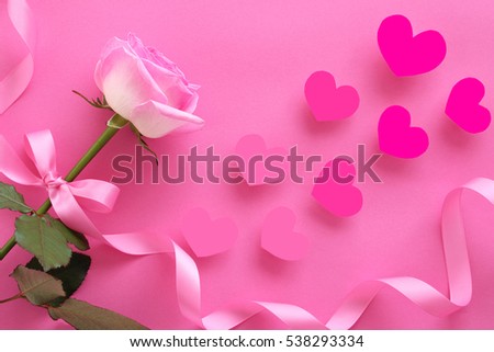 Beautiful rose with handmade heart and ribbon on pink background, top view