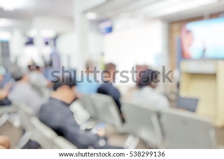 Blur abstract background international people travellers working on computer laptop while waiting for airplane flight at terminal hall. Blurry passengers wait to go aboard sit on rows of chairs.