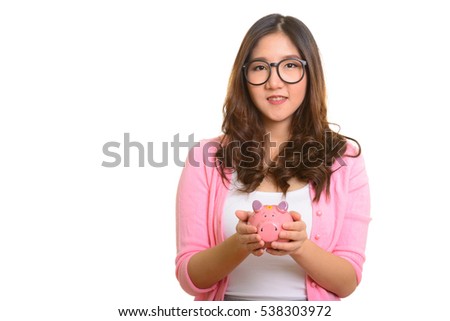 Young happy Asian woman holding piggy bank