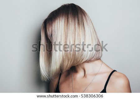 Model with unrecognizable face with blond shiny hair. Woman bob haircut styling.