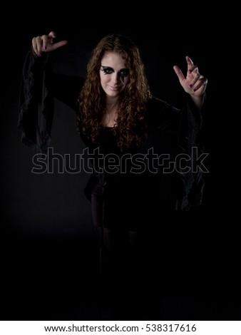 Teen girl dressed up for halloween a witch on dark black background