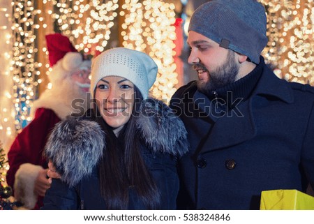 Happy attractive couple enjoy in a christmas market at night. Beautiful bokeh lights background.Under exposed photo