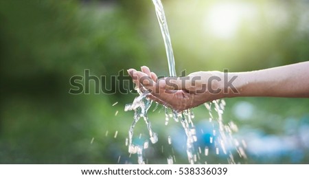 Water pouring in woman hand on nature background, environment issues Royalty-Free Stock Photo #538336039