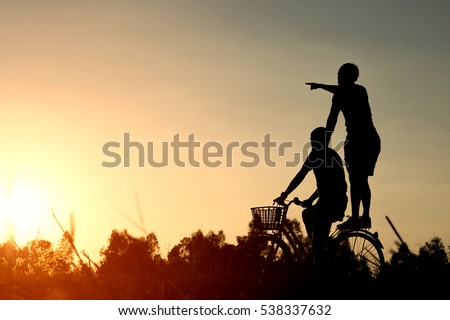 Joyful young man riding a bicycle together. Best friends having fun on a bike at the meadow. Royalty-Free Stock Photo #538337632