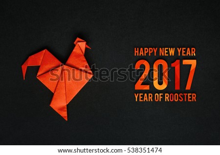 Red fire paper folded rooster handmade origami craft on black background. Nice horizontal holiday greeting card, postcard. Happy new year 2017 year of rooster text letters.