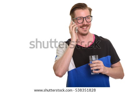 Young happy Caucasian man talking on mobile phone and holding glass of water