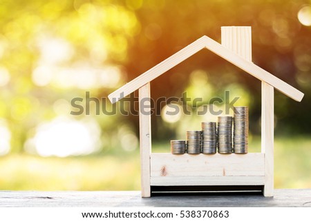 Saving money for real estate concept, a stacking gold coins with growing put in a model home on the table on bokeh background in the public park. Royalty-Free Stock Photo #538370863
