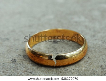 Cracked gold wedding ring -- divorce or infidelity concept                              Royalty-Free Stock Photo #538377070