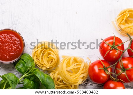 Italian food background with vine tomatoes, basil, tagliatelle pasta on white background Top view