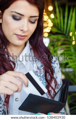 Shopper takes the credit card out of wallet.Worried girl or woman takes a bank card from the wallet