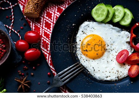 Breakfast set for christmas. Pan of fried eggs. Cucumber and cherry-tomatoes with Turkish bagels on dark table surface, top view. Christmas Breakfast.