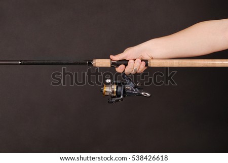 Man's hand holding a fishing rod on a black background