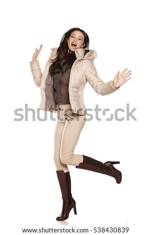young happy woman in a winter jacket and boots jumping on a white background