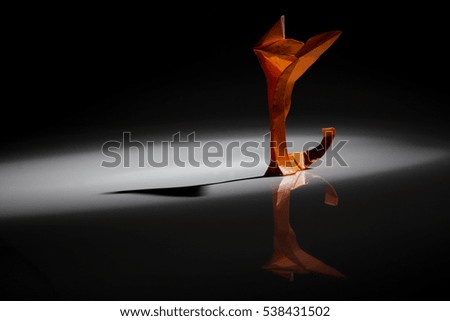 An orange origami cat over dark background