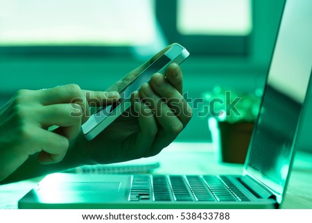 Computer person working on the phone in green light like hacker