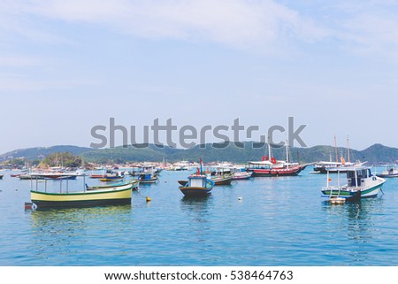 Colorful fishing boats in tropical turquoise water with mountain scenery in the background. 