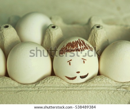 eggs white with drawn mans face close up photo. Raw eggs, crater egg