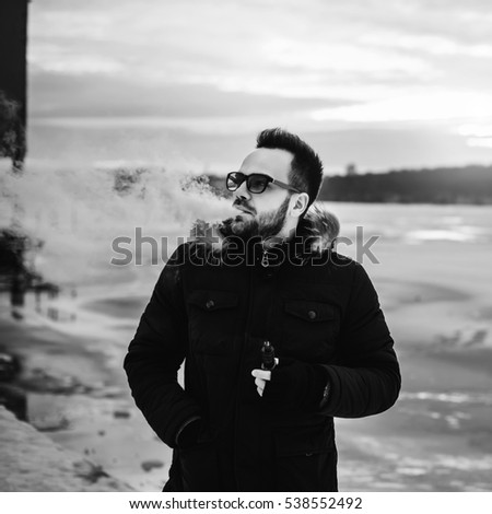 Man with beard smoke electronic cigarette