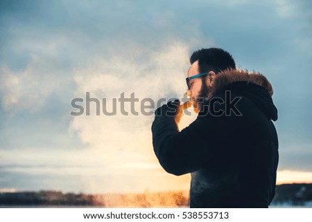 Man with beard vape electronic cigarette outdoor.