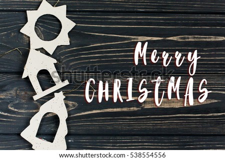 merry christmas text sign on simple christmas eco toys on stylish black wooden background in border line. space for text. holiday greeting card concept. unusual creative top view 